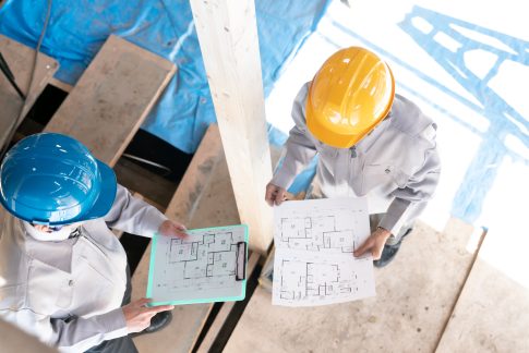 Zwei Männer besprechen auf Baustelle Baupläne